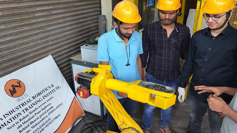 Trainees learning industrial robotics programming on a real robot arm