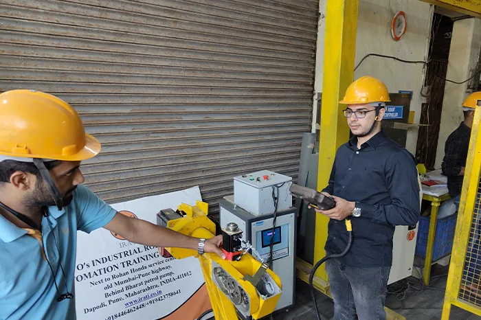 IRATI trainee operating an industrial robot with a teach pendant at the Dapodi, Pune workshop
